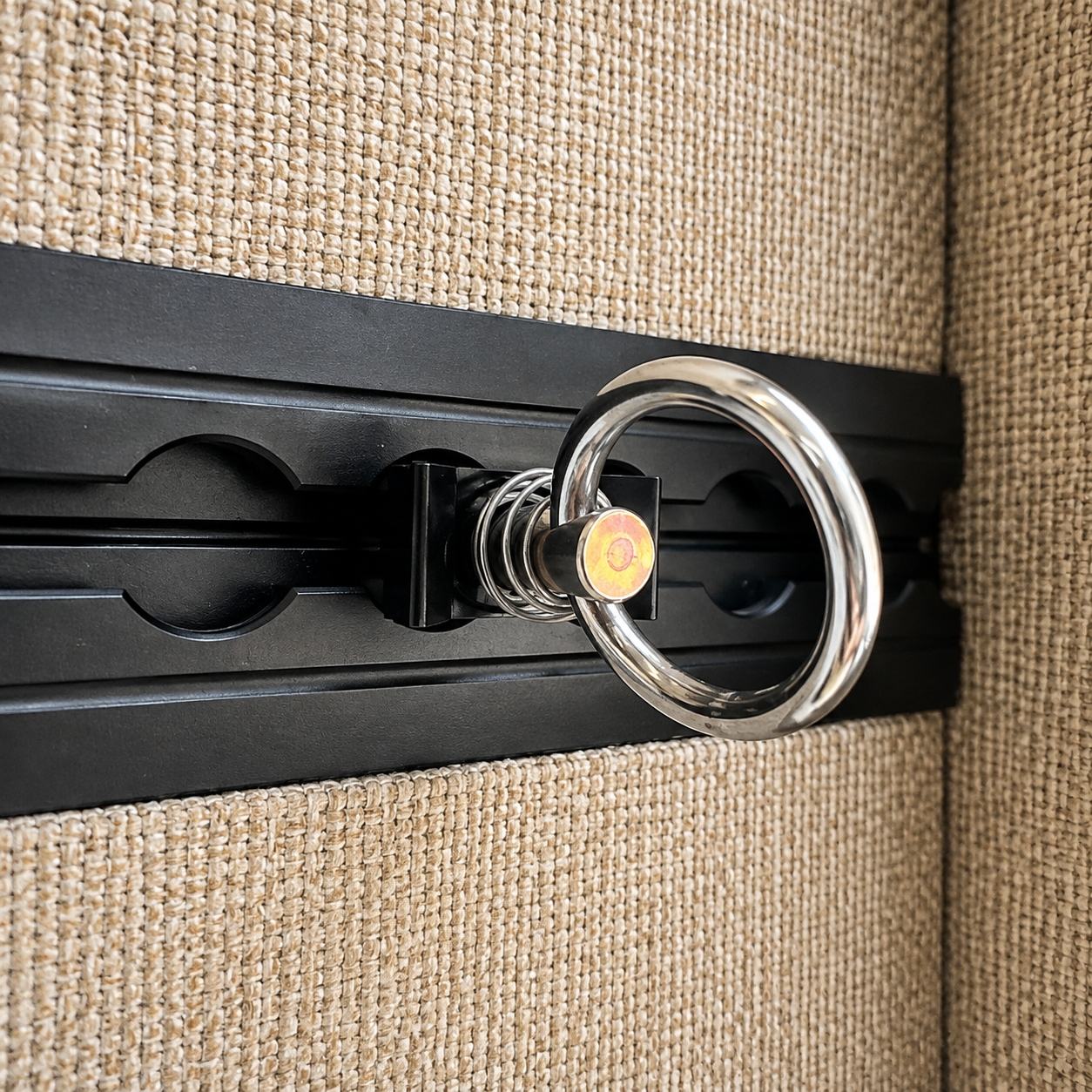 Silver tie-down ring fitting installed in black L-track on a camper van wall